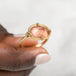 Gold ring with an Oregon sunstone held in hand against a neutral background