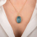Gold necklace with an aquamarine gemstone on a person's neck
