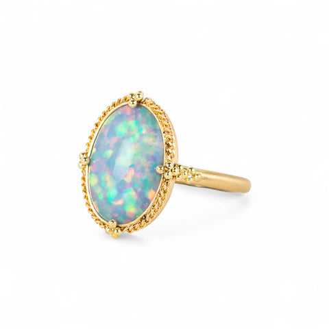 Gold ring with an Ethiopian opal stone on a white background