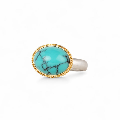 Turquoise ring with gold bezel and sterling silver band on white background