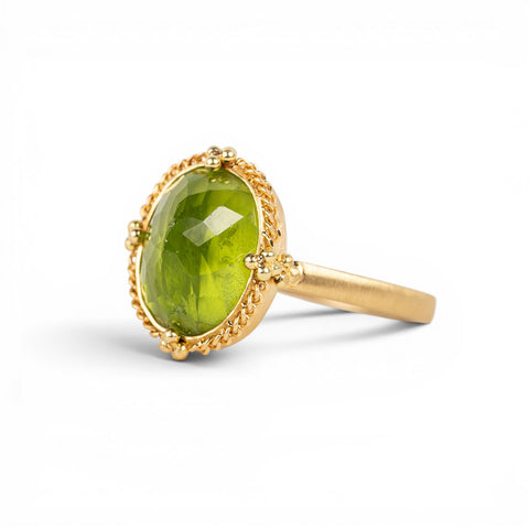 Gold ring with a peridot gemstone on a white background