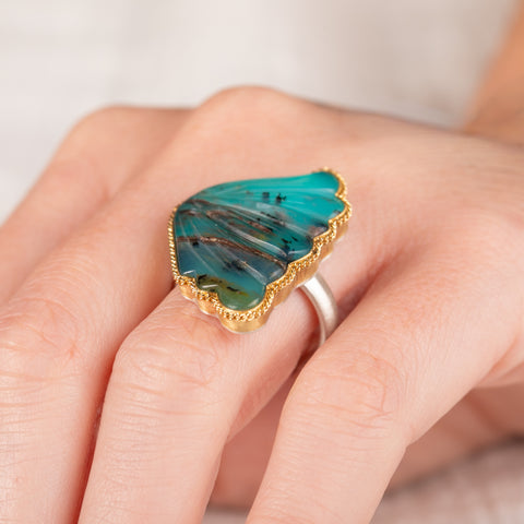Hand wearing a peruvian opal wing ring with gold bezel and silver band