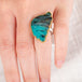 Hand wearing a Peruvian Opal wing ring with gold bezel and silver band