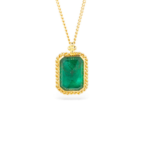Gold necklace with a rectangular emerald gemstone pendant on a white background