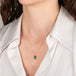 Gold necklace with a rectangular emerald gemstone pendant on a person