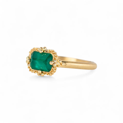 Gold ring with an emerald gemstone on a white background