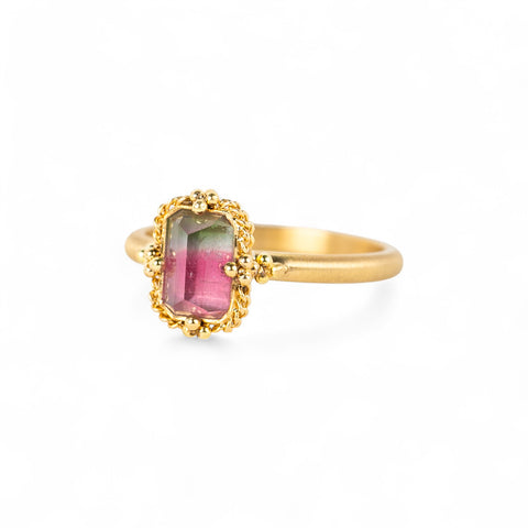 Gold ring with a watermelon tourmaline gemstone on a white background