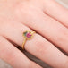 Gold ring with a watermelon tourmaline gemstone worn on a persons finger