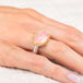 Gold and silver ring on a person's finger with a pink opal stone