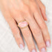 Gold and silver ring with a pink opal stone on a hand against a light background