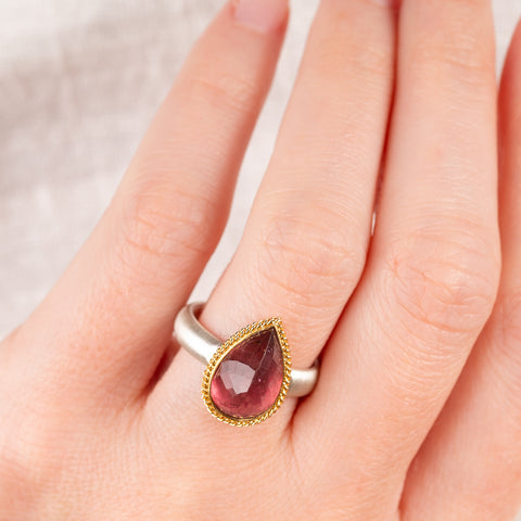Hand wearing a pink tourmaline ring with gold bezel and silver band