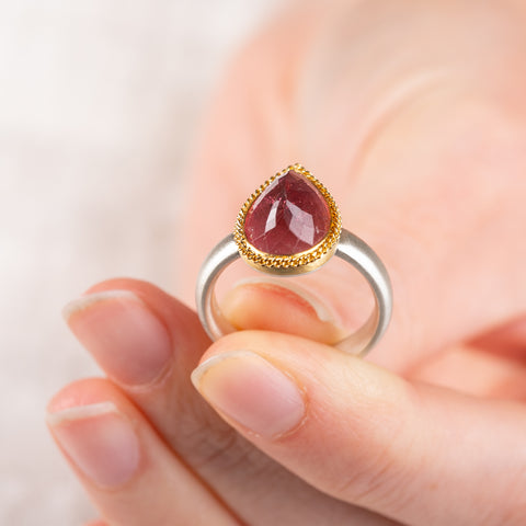 Close up of a pink tourmaline ring with gold bezel and silver band