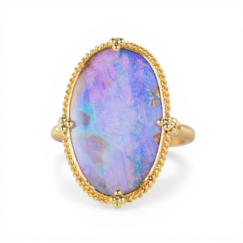 Gold ring with a boulder opal stone on a white background
