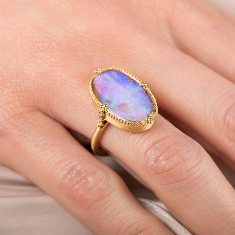 Gold ring with a colorful boulder opal gemstone on a hand