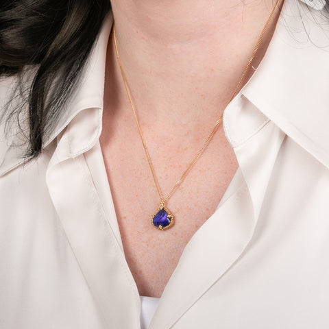 Tanzanite pendant on a gold chain against a person