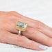 Gold and silver ring featuring a quartz with pyrite stone on a person's finger with a white background