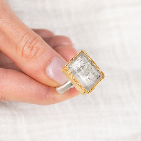 Ring with a gold frame, silver band and quartz with pyrite stone held in hand
