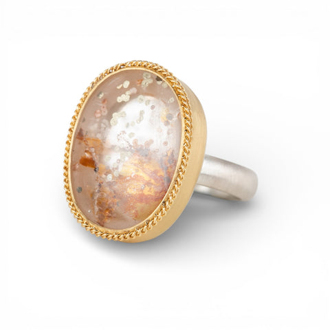 Ring with a gold bezel, silver band and quartz with pyrite stone on a white background