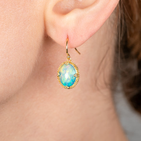 Gold earrings with Ethiopian opals worn on a person