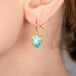 Gold earrings with Ethiopian opals worn on a person