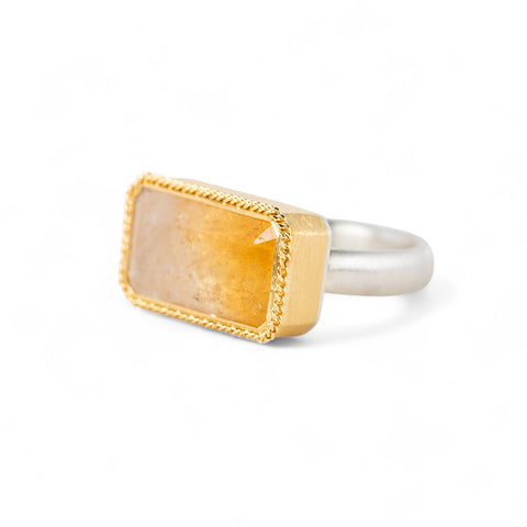 Gold and silver ring with a rectangular citrine stone on a white background