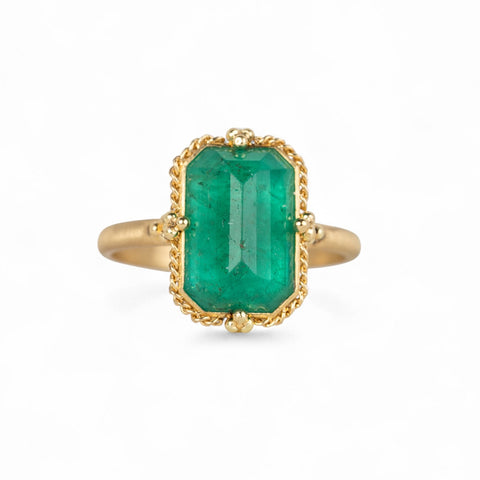 Gold ring with an emerald gemstone on a white background