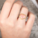 Heart-shaped ring with rhodochrosite stone, gold setting and silver band on a person's finger
