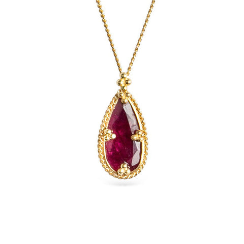 Gold necklace featuring a ruby gemstone on a white background