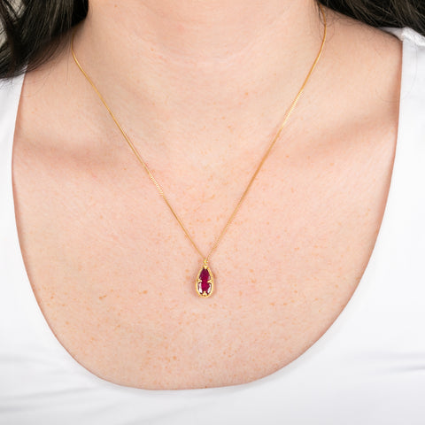 Gold necklace featuring a ruby gemstone on a person