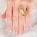 A hand wearing a rutilated quartz ring with an 18k gold bezel and sterling silver band