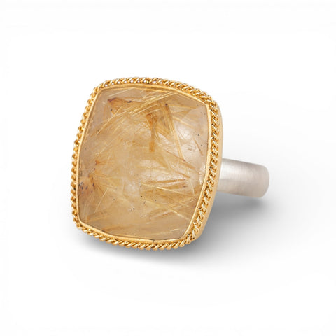 Gold and silver ring with a rutilated quartz stone on a white background
