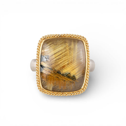 Gold and silver ring with a rutilated quartz stone on a white background