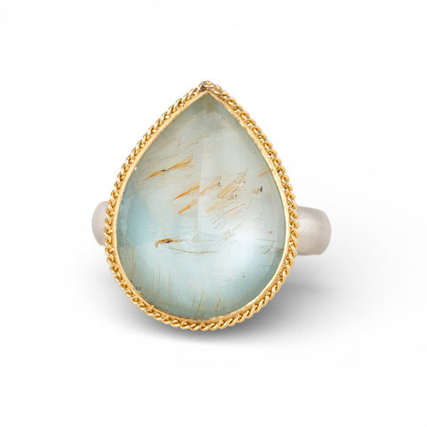 Teardrop-shaped gold and silver ring with rutilated topaz stone on a white background