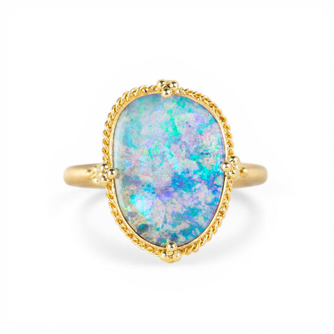 Ring with a boulder opal stone and gold band on a white background