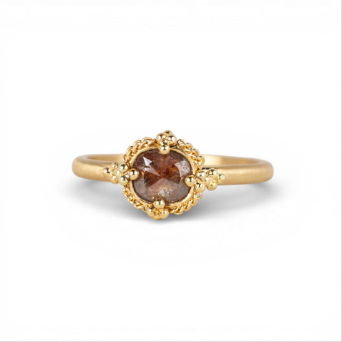 Gold ring with a brown diamond on a white background