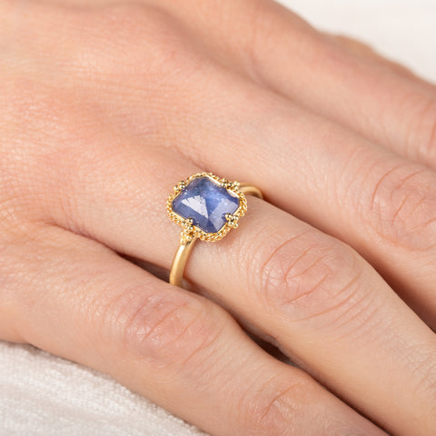 Gold ring with a blue tanzanite gemstone on a person's finger