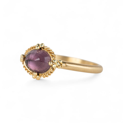 Gold ring with a spinel gemstone on a white background