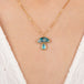 Gold necklace with mushroom pendant featuring boulder opal and aquamarine stones on a person
