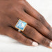 Gold and silver ring with a moonstone on a person's finger against a white background