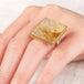 A close up of a hand wearing a handcrafted ring made with a rutilated quartz, 18k gold bezel and sterling silver band