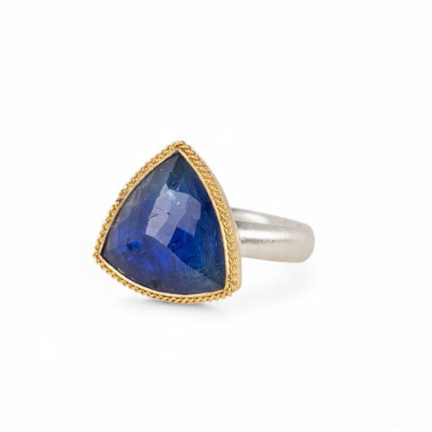 Handmade ring with a tanzanite gemstone, gold bezel and sterling silver band on a white background