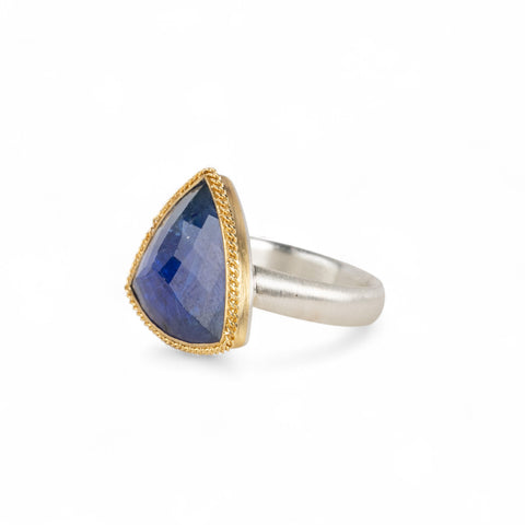 Handmade ring with a tanzanite gemstone, gold bezel and sterling silver band on a white background