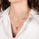 Gold necklace with a tanzanite gemstone on a person wearing a white top.