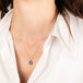 Gold necklace with a blue tanzanite pendant on a person wearing a white shirt.