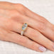 Gold and silver ring with a topaz gemstone on a hand against a white background