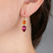 Gold earrings with tourmaline and fire opal gemstones worn on a person