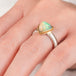 Close up of hand wearing an Ethiopian opal ring with 18k gold bezel and sterling silver band