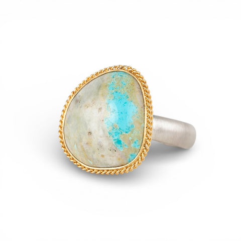 Gold and silver ring with a turquoise stone on a white background