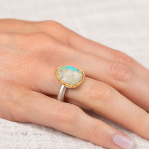 Gold and silver ring with a turquoise stone on a hand