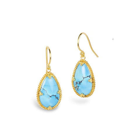 A pair of gold drop earrings featuring teardrop-shaped light blue turquoise stones with natural matrix veining, set in a textured gold bezel, on a clean white background.